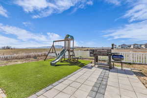 View of playground featuring a patio and a gate
