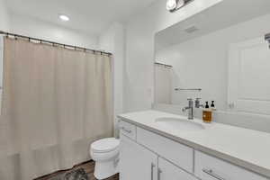 Bathroom featuring vanity, dark wood-type flooring, shower / tub combo, and recessed lighting