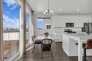 Kitchen featuring white cabinetry, a breakfast bar, dark wood-type flooring, tasteful backsplash, and stainless steel appliances