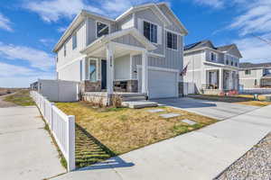 Craftsman-style home with an attached garage, board and batten siding, concrete driveway, a porch, and stone siding