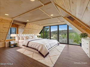 Virtually Staged Bedroom with wood walls, dark wood-type flooring, multiple windows, and a mountain view
