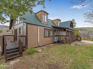 View of property exterior featuring a metal roof and a wooden deck