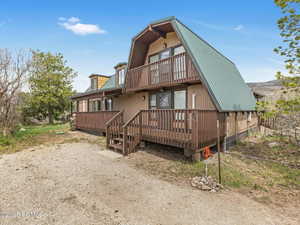 Rear view of house with a metal roof, a balcony, and a gambrel roof