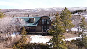 Snow covered house featuring a mountain view, a balcony, a metal roof, and a gambrel roof