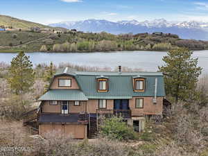 Back of property featuring a metal roof, a deck with water view, and a gambrel roof