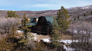 Snow covered back of property featuring a metal roof, a gambrel roof, a deck with mountain view, and a balcony
