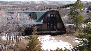 View of front of home with a gambrel roof, a balcony, a deck with mountain view, and a metal roof