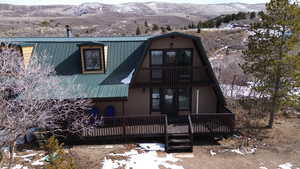 View of front of property with a gambrel roof, a balcony, a deck with mountain view, and a metal roof
