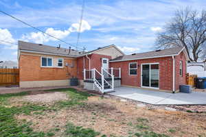 Back of house with a patio area, brick siding, and roof with shingles