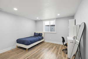 Bedroom featuring light wood-style floors, a desk, recessed lighting, and a textured ceiling