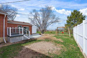 Fenced backyard with a wooden deck and a playground