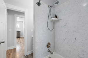 Bathroom with dark wood finished floors, vanity, and bathing tub / shower combination