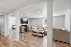 Living area with a textured ceiling, light wood-type flooring, a warm lit fireplace, and recessed lighting