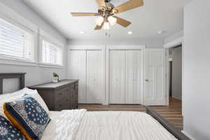 Bedroom with multiple closets, dark wood finished floors, ceiling fan, and recessed lighting