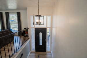 Foyer with wood finished floors and suspended lighting