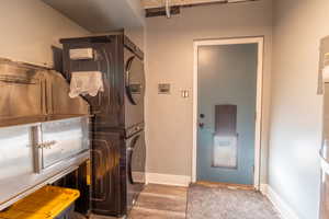 Laundry area with light wood-type flooring and stacked washer and dryer
