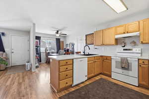 Kitchen with a peninsula, white appliances, light countertops, and light wood-style flooring