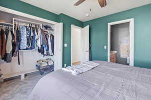 Bedroom with a closet, light colored carpet, a ceiling fan, and connected bathroom