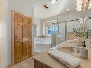 Full bath with a shower stall, double vanity, a bath, and light tile patterned floors