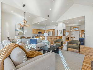 Living area with hanging lights, light wood-style flooring, and lofted ceiling