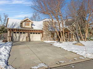 View of front of house with stone siding, concrete driveway, and an attached garage
