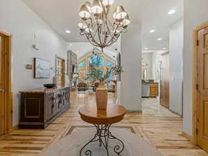 Hall featuring suspended lighting, light wood-style flooring, and lofted ceiling