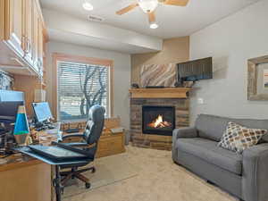 Office space with light colored carpet, ceiling fan, a stone fireplace, and recessed lighting
