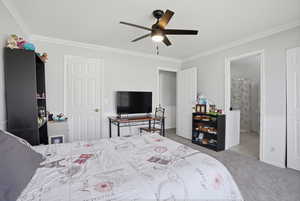 Bedroom featuring light colored carpet, a ceiling fan, ornamental molding, and ensuite bathroom