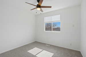 Spare room featuring carpet and ceiling fan