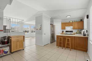 Kitchen featuring a peninsula, light countertops, a kitchen breakfast bar, electric stove, and vaulted ceiling