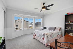 Carpeted bedroom featuring crown molding and a ceiling fan