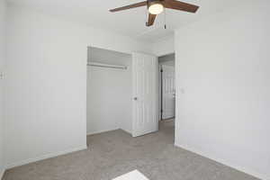 Unfurnished bedroom featuring light colored carpet, ceiling fan, and a closet