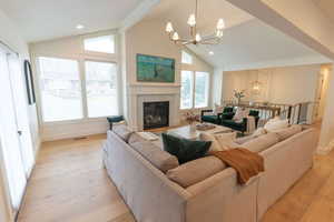 Living area featuring suspended lighting, plenty of natural light, light wood finished floors, and a glass covered fireplace