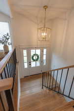 Foyer entrance with light wood-style flooring, hanging lights, and a high ceiling