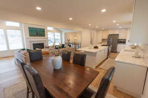 Dining space featuring light wood-style floors, recessed lighting, and a glass covered fireplace