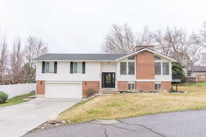 Split foyer home with brick siding, driveway, a garage, a chimney, and entry steps