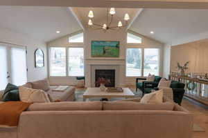 Living area with a premium fireplace, suspended lighting, wood finished floors, plenty of natural light, and a high ceiling