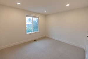 Spare room featuring light colored carpet and recessed lighting