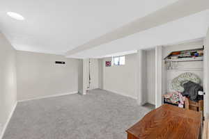 Basement with light colored carpet and baseboards