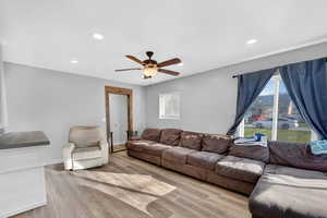 Living room featuring light wood-style flooring, a ceiling fan, and recessed lighting