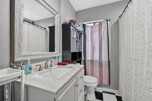 Full bath featuring a shower with curtain, vanity, and light floors