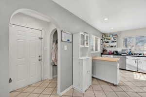 Kitchen with dishwasher, white cabinetry, butcher block counters, light tile patterned floors, and recessed lighting