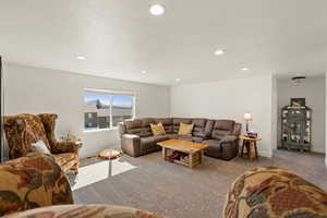 Carpeted living room featuring recessed lighting and a textured ceiling
