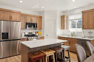 Kitchen with stainless steel appliances, recessed lighting, a breakfast bar area, light wood-style floors, and a center island