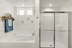 Primary suite bathroom featuring a shower stall and a garden tub