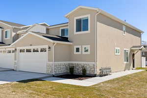 View of home's exterior featuring stone siding, a lawn, stucco siding, and concrete driveway