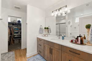 Primary suite bathroom featuring vanity, a stall shower, light wood finished floors, a spacious closet, and recessed lighting