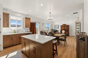 Kitchen featuring wood finish cabinets, suspended lighting, a center island, and light wood-style flooring