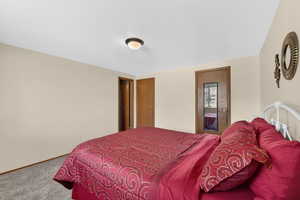 Carpeted bedroom featuring ensuite bath and a textured ceiling