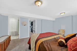Bedroom featuring light carpet, connected bathroom, and a walk in closet